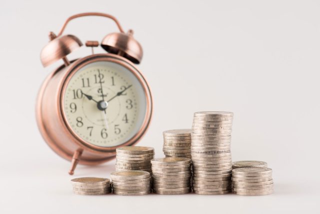 a pile of coins sitting next to a clock.