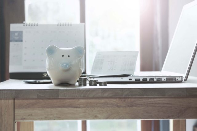 a piggy bank sitting on a desk next to a laptop.